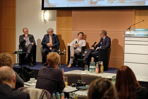 Podiumsdiskussion mit vier Geschäftsleuten auf einer Bühne im Kongress-Centrum Koelnmesse, die vor Publikum mit Mikrofonen über ein Thema sprechen