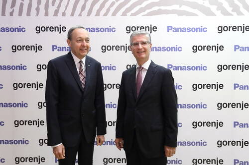 Zwei geschäftsmänner im Anzug posieren lächelnd vor einer Sponsorenwand mit den Logos von Panasonic und Gorenje.