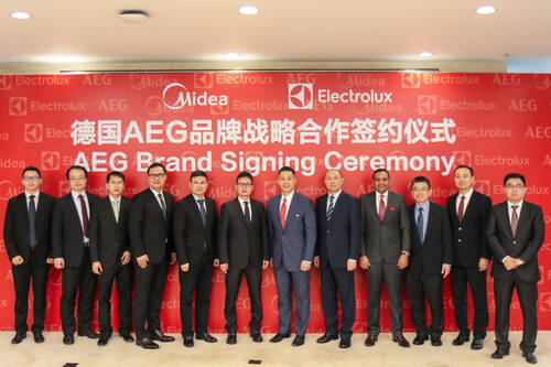 Manager und Unternehmensvertreter stehen in Anzügen vor roter Medienwand bei der AEG Brand Signing Ceremony von Midea und Electrolux.