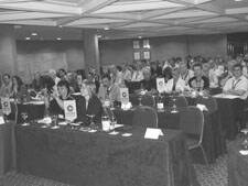 Teilnehmerinnen und Teilnehmer sitzen dicht gedrängt in einem Konferenzraum und verfolgen aufmerksam eine Präsentation an der Vorderseite des Saals