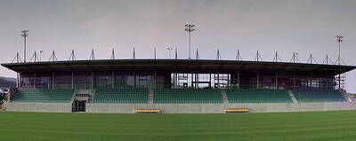 Leere überdachte Tribüne eines modernen Fußballstadions mit grünen Sitzreihen und gepflegtem Rasen im Vordergrund