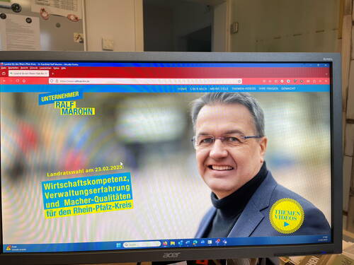 Kandidat für die Landratswahl 2025 mit Brille und dunklem Sakko lächelt auf einer Wahlkampf-Webseite mit gelb-blauer Schrift über Wirtschafts- und Verwaltungskompetenz im Rhein-Pfalz-Kreis