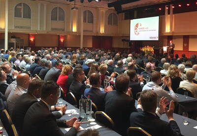 Großes Publikum in einem Konferenzsaal, das einem Vortrag über „Handel 4.0 – samenwerken en versterken“ zuhört und Beifall klatscht