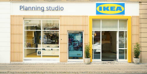 Moderne IKEA-Planning-Studio-Filiale mit großen Schaufenstern, gelbem Eingangrahmen und Einblick in hell beleuchtete Ausstellungsräume
