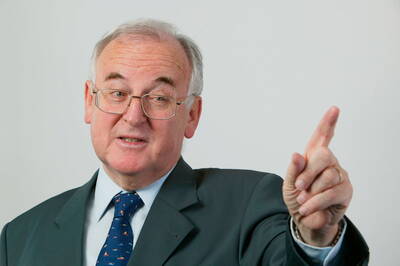 Älterer Mann im Anzug und mit Brille hebt mahnend den Zeigefinger und spricht, als würde er einen wichtigen Punkt betonen.