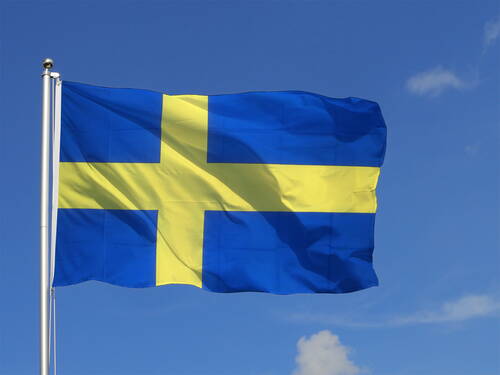Gelb-blaues skandinavisches Kreuz weht als schwedische Nationalflagge vor klarem, blauem Himmel