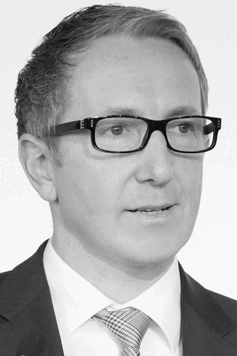 Mittelalter Mann mit Brille im Anzug spricht, frontal im Porträt in Schwarz-Weiß aufgenommen