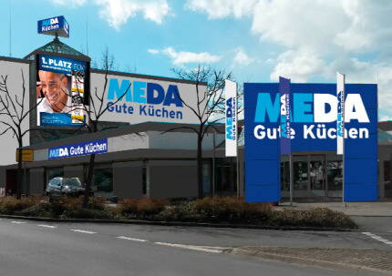 Großes Küchenfachgeschäft „MEDA Gute Küchen“ an einer Straßenkreuzung mit markanten blauen Werbeschildern und Glasfassade bei Tageslicht