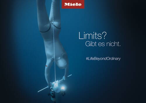 Freitaucher hängt kopfüber an einem Seil in der tiefblauen Unterwasserwelt, erreicht leuchtende Markierung und Werbeslogan „Limits? Gibt es nicht. #LifeBeyondOrdinary“ für Miele.
