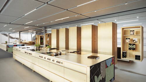 Modern gestaltete Showküche mit langen Kochinseln aus hellem Holz, Induktionskochfeldern, frischen Kräutertöpfen und beleuchteten Regalen mit Kochbüchern in einem großzügigen, lichtdurchfluteten Raum