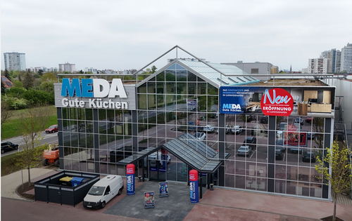 Modernes MEDA-Gute-Küchen-Fachgeschäft mit Glasfassade und großem Schild zur Neueröffnung inmitten einer städtischen Umgebung