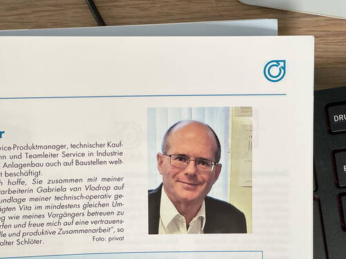 Mittelalterlicher Mann mit Brille lächelt im Porträtfoto in einem gedruckten Magazin neben einem deutschen Textabschnitt über seine berufliche Tätigkeit
