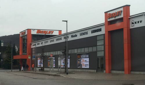 Elektronikmarkt Berlet mit orange-grauer Fassade und Markenlogos wie Bosch, Sony und Siemens an einem bewölkten Tag