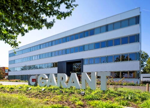 Moderner Bürokomplex mit großem „GARANT“-Schriftzug im begrünten Vorgarten an einem sonnigen Tag