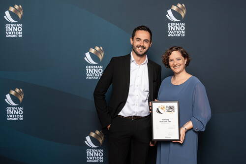 Zwei lächelnde Personen in Businesskleidung präsentieren bei der Verleihung des German Innovation Award 2019 eine gerahmte Auszeichnung für das Produkt „Samsung Dual Cook Flex“.