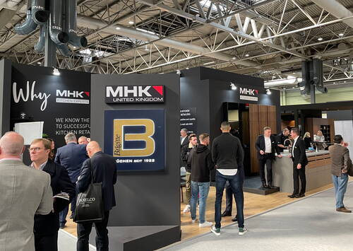 Messemessestand von MHK Kitchen Experts mit Besuchern im Gespräch vor modernen Küchenpräsentationen und großen Markenlogos in einer hellen Ausstellungshalle