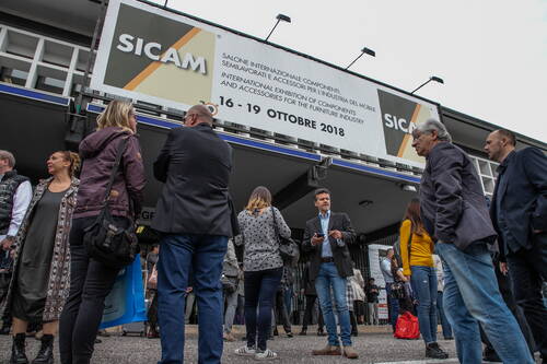 Besucherinnen und Besucher versammeln sich vor dem Eingang der SICAM-Messe 2018 in Pordenone unter einem großen Banner zur internationalen Ausstellung für Möbelkomponenten.