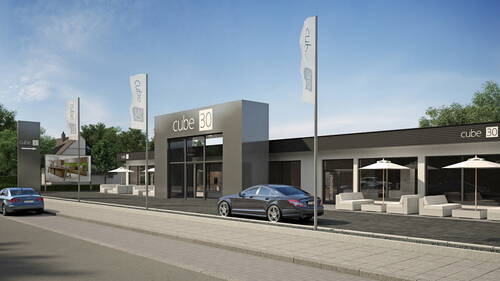 Modernes Ausstellungsgebäude „cube 30“ mit großer Glasfront, davor geparktem Auto und Lounge-Bereich mit weißen Sitzmöbeln und Sonnenschirmen entlang einer ruhigen Straße
