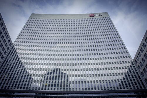 Spiegelnde Glasfassade eines hohen LG-Bürogebäudes, aus der Froschperspektive vor bewölktem Himmel aufgenommen