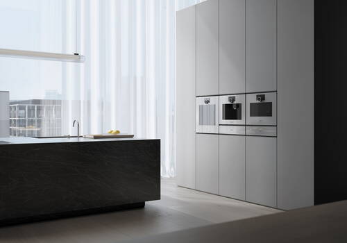 Minimalistische, helle Designküche mit schwarzer Kücheninsel, eingebauten Edelstahl-Geräten und bodentiefen Fenstern mit halbtransparenten Vorhängen