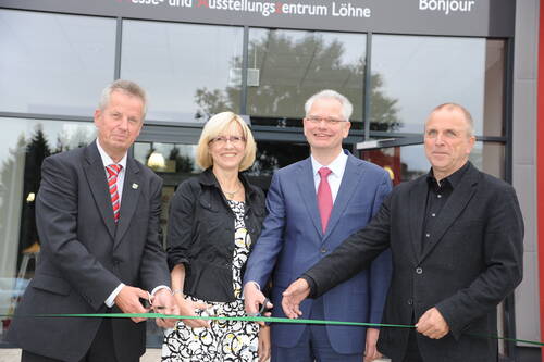 Vier Personen im Business-Outfit lächeln vor dem Messe- und Ausstellungszentrum Löhne und halten gemeinsam ein grünes Band zur feierlichen Eröffnung gespannt
