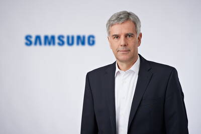 Geschäftsmann im dunklen Anzug mit weißem Hemd steht vor unscharfem Samsung-Logo auf hellem Hintergrund
