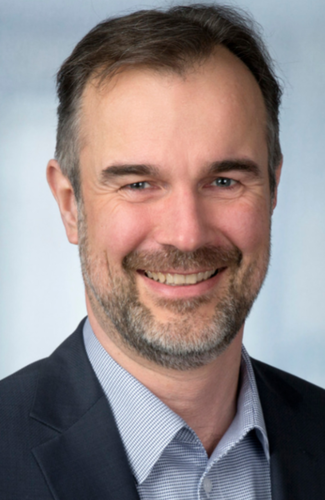 Lächelnder Mann mittleren Alters im Anzug vor neutralem Hintergrund in einem professionellen Porträtfoto