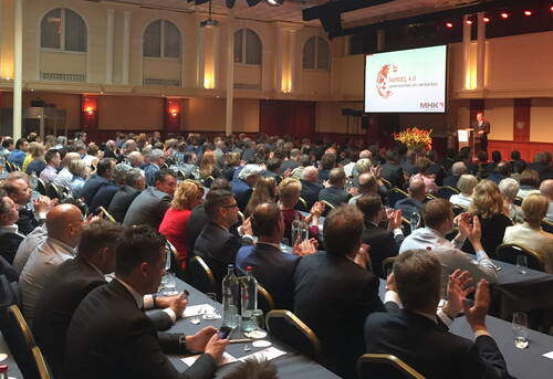Großes Publikum in einem Konferenzsaal, das einem Vortrag über „Handel 4.0 – samenwerken en versterken“ zuhört und Beifall klatscht
