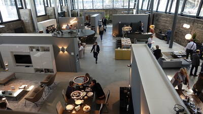 Geräumige Möbelausstellung in einer Industriehalle, in der Besucher zwischen modern eingerichteten Wohn- und Essbereichen mit Designerleuchten und Dekoration umhergehen und beraten werden
