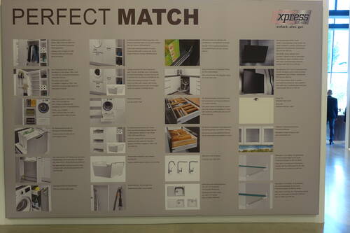 Große Messewand mit der Überschrift „Perfect Match“, die verschiedene modulare Küchenschrank‑ und Hauswirtschaftslösungen mit Fotos, kurzen Beschreibungen und dem Markenlogo „xpress Küchen“ präsentiert.