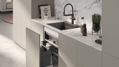 Minimalistische Küche mit Marmorarbeitsplatte, schwarzer Spüle, offenem Auszugsschrank und dekorativen Accessoires wie Kochbüchern, Ölflaschen und einem Kräutertopf.