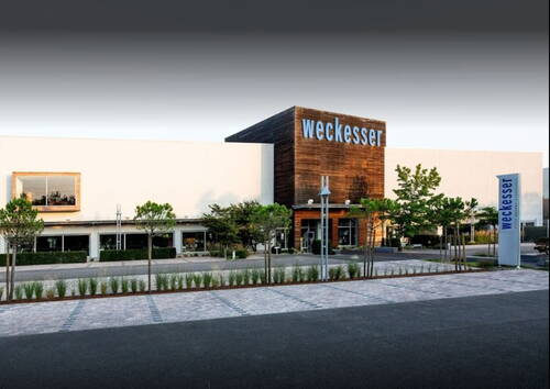 Moderner Unternehmenssitz von Weckesser mit großer Holzfassade, begrüntem Vorplatz und breitem Eingangsbereich an einer ruhigen Straße