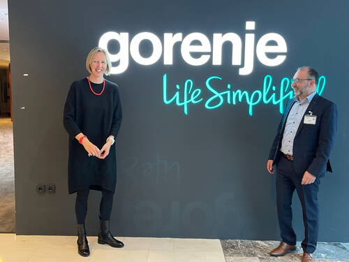 Zwei lächelnde Personen stehen im Eingangsbereich vor einer beleuchteten Wand mit dem Firmenlogo „gorenje“ und dem Slogan „Life Simplified“