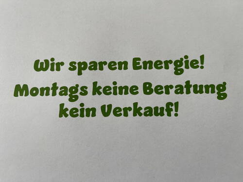 Hinweisschild mit grünem Text, der wegen Energiesparen darauf aufmerksam macht, dass montags keine Beratung und kein Verkauf stattfindet