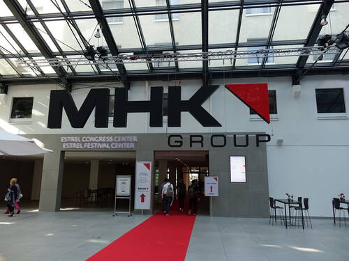 Eingangsbereich des Estrel Congress Centers mit großem MHK Group Schriftzug und rotem Teppich, auf dem Besucher zum Tagungscheck-in geleitet werden