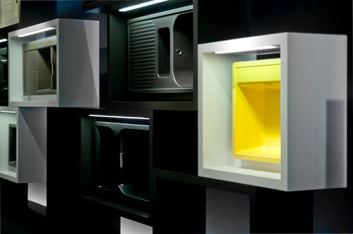 Moderne Küchen- und Spülbeckenmodule in schwarzen und weißen Rahmen, mit einem leuchtend gelben Becken als farbigem Akzent in einer geometrischen Wandinstallation