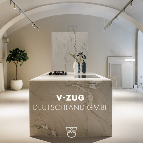 Minimalistische Designküche mit freistehender Marmor-Kochinsel, eingebautem Kochfeld, Blumenvase und dezentem V-ZUG Deutschland GmbH Branding in hell beleuchtetem Showroom