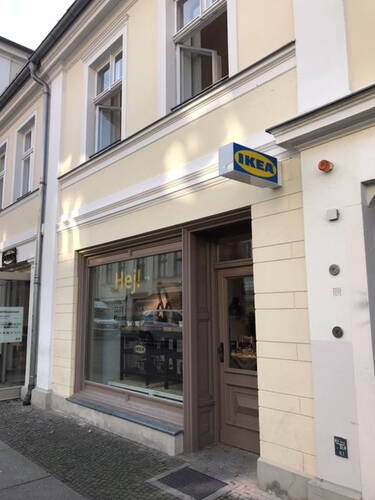 Kleines IKEA-Geschäft im Erdgeschoss eines hellen Altbauhauses mit Schaufenster und seitlichem Eingang an einer ruhigen Stadtstraße