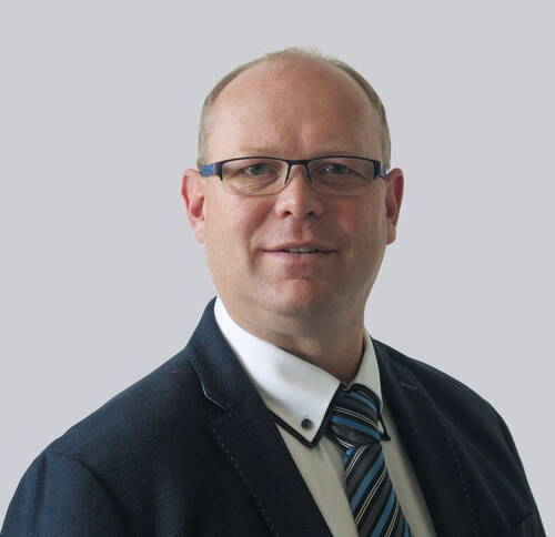 Mittelalterlicher Mann mit Brille im Business-Anzug und gestreifter Krawatte vor neutral grauem Hintergrund