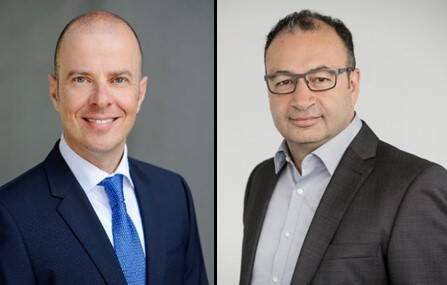 Zwei geschäftlich gekleidete Männer stehen jeweils im Porträt nebeneinander, links mit blauem Anzug und Krawatte lächelnd in die Kamera, rechts mit dunklem Anzug, Brille und neutralem Gesichtsausdruck vor hellem Hintergrund.
