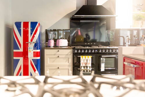 Bunte Designerküche mit Kühlschrank im Union-Jack-Design, schwarzem SMEG-Gasherd und rosa Kleingeräten auf der Arbeitsplatte
