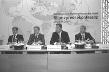 Vier Manager sitzen bei einer Bilanzpressekonferenz von BSH Bosch und Siemens Hausgeräte GmbH an einem Konferenztisch mit Mikrofonen und Namensschildern
