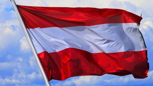 Rot-weiß-rote Nationalflagge flattert im Wind vor blauem, leicht bewölktem Himmel