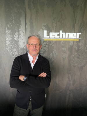 Älterer Mann mit Brille und verschränkten Armen steht vor einer Wand mit dem Schriftzug „Lechner“