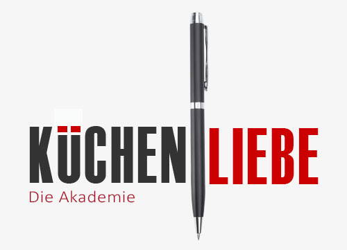 Schwarzer Kugelschreiber trennt das zweifarbige Logo „Küchenliebe – Die Akademie“ mit stilisiertem Küchensymbol im Buchstaben Ü