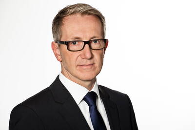 Mittelalterlicher Geschäftsmann mit Brille im dunklen Anzug und blauem Schlips vor weißem Hintergrund, der ernst in die Kamera blickt