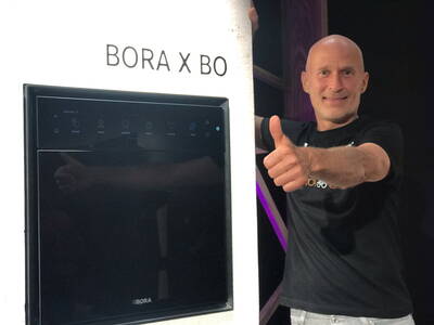 Mann mit erhobenem Daumen steht neben einem eingebauten BORA X BO Gerät in moderner Umgebung