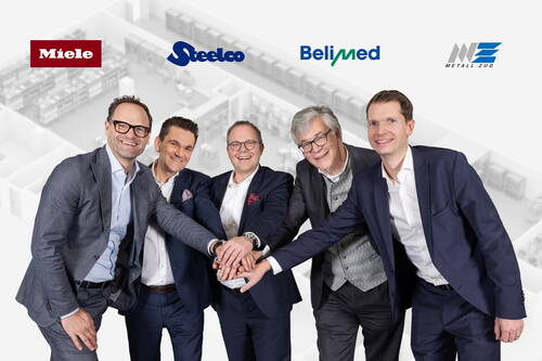 Sechs Manager in Anzügen stehen lächelnd im Halbkreis und legen zur Bekräftigung einer Kooperation ihre Hände übereinander, hinter ihnen sind Unternehmenslogos und ein schematischer Grundriss einer Produktionsanlage zu sehen.