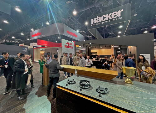 Menschenmenge auf einer Küchenmesse versammelt sich an einem modernen Häcker-Ausstellungsstand mit Kochinsel, Gasfeldern und goldener Trophäe vor großen Markenbannern unter der Hallendecke