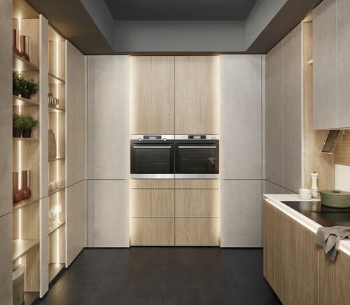 Modernes, in warmem Holz und Betonoptik gestaltetes Küchendesign mit integrierten Doppelbacköfen, offen beleuchteten Regalen und einer Kochinsel mit Induktionskochfeld.